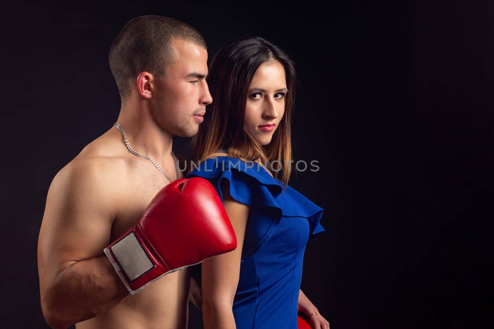 Boxer hugs slender girl on black background