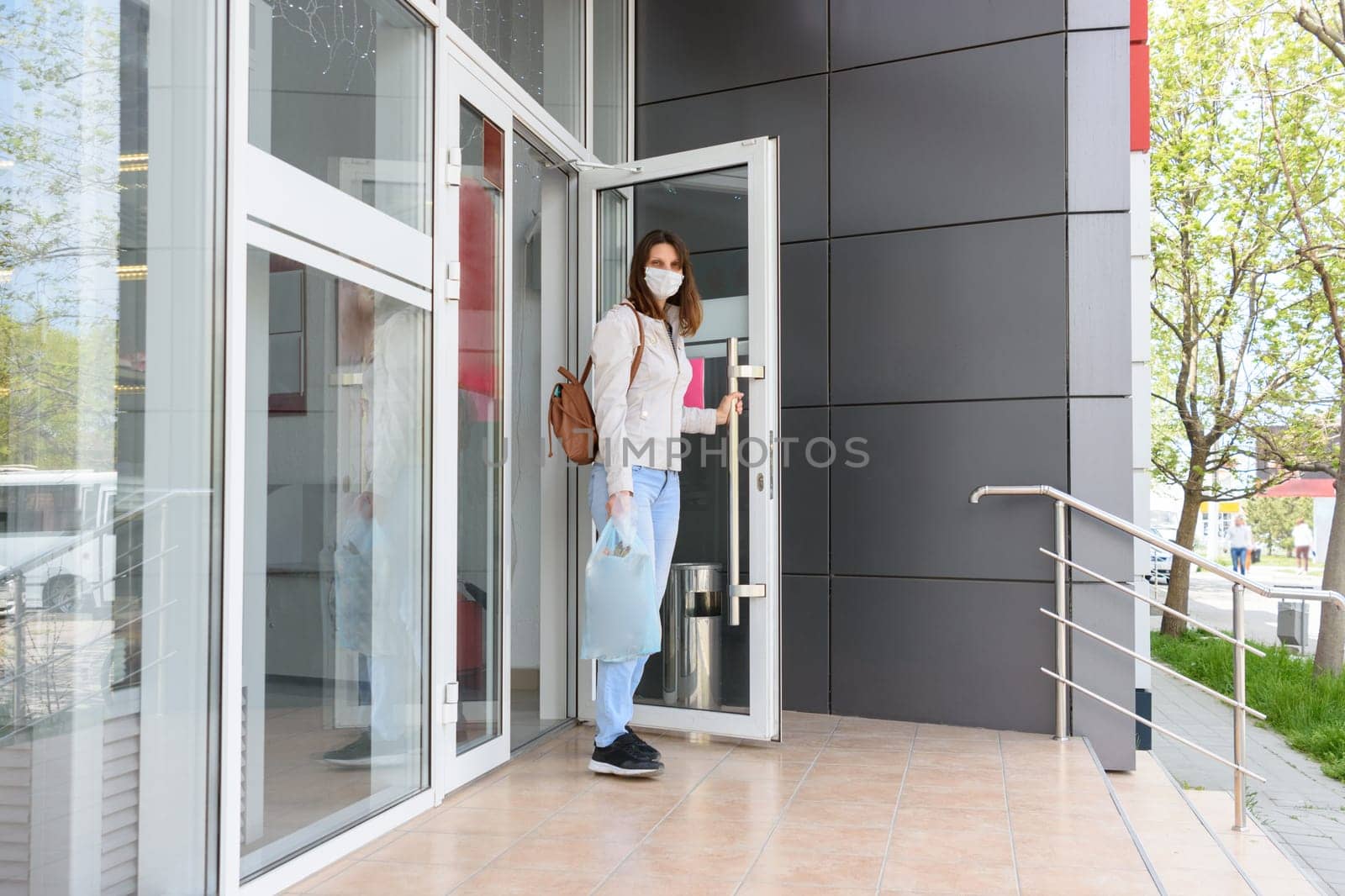 Girl walks out of the store wearing a medical mask with shopping