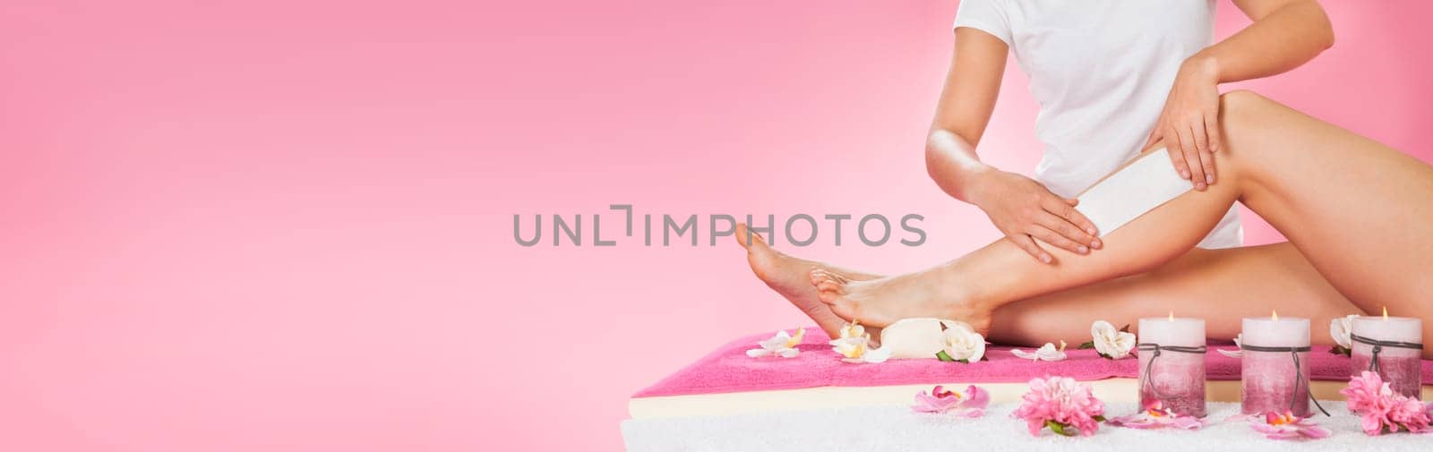 Midsection of female therapist waxing customer's leg at beauty spa