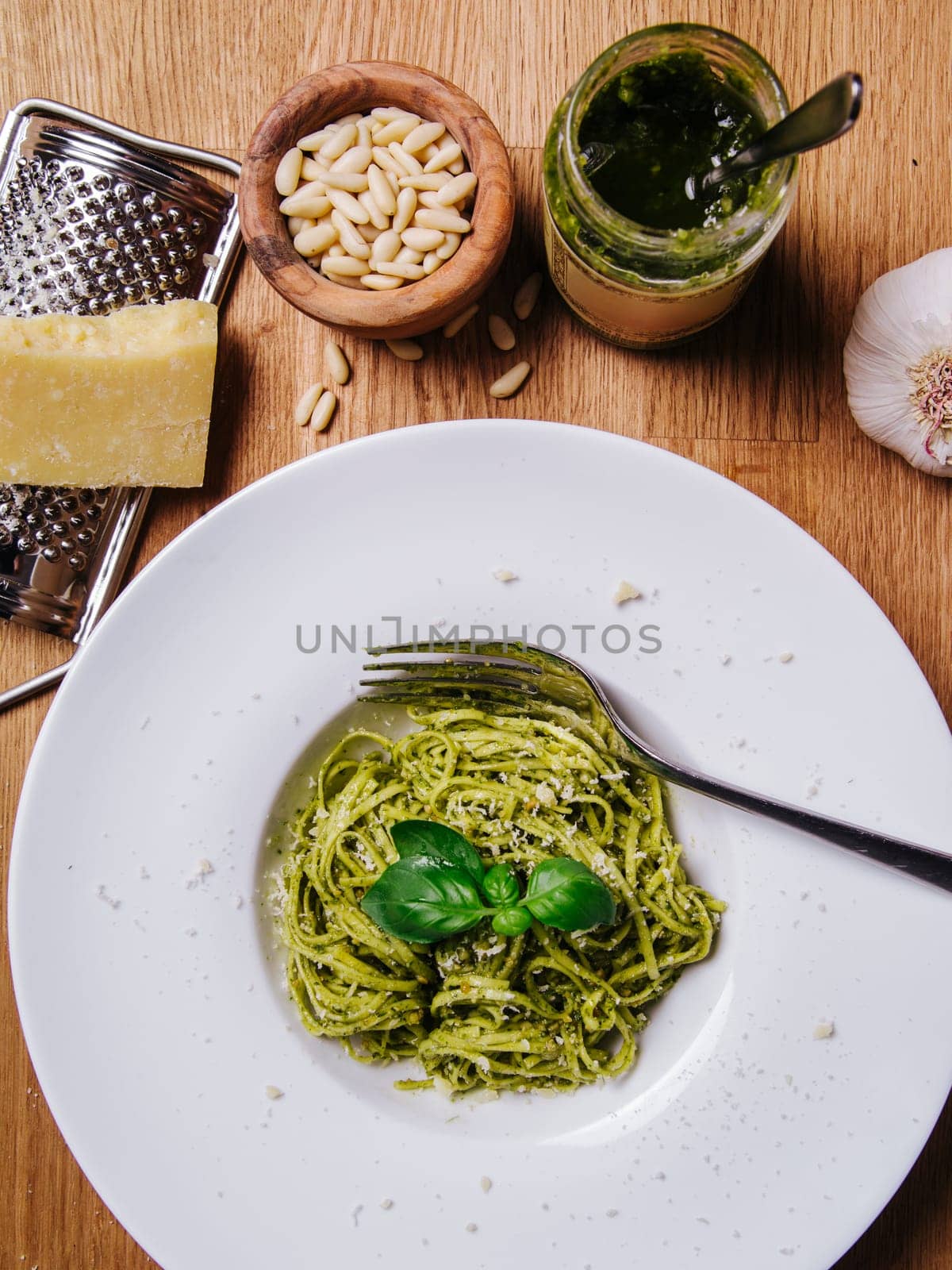 Bowl of basil pesto and pasta on an old wood table.