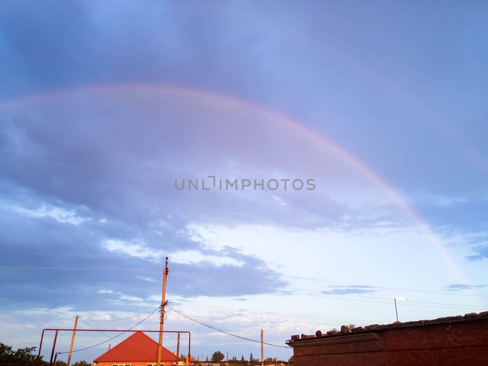 Rainbow over the village. Rainbow after rain.