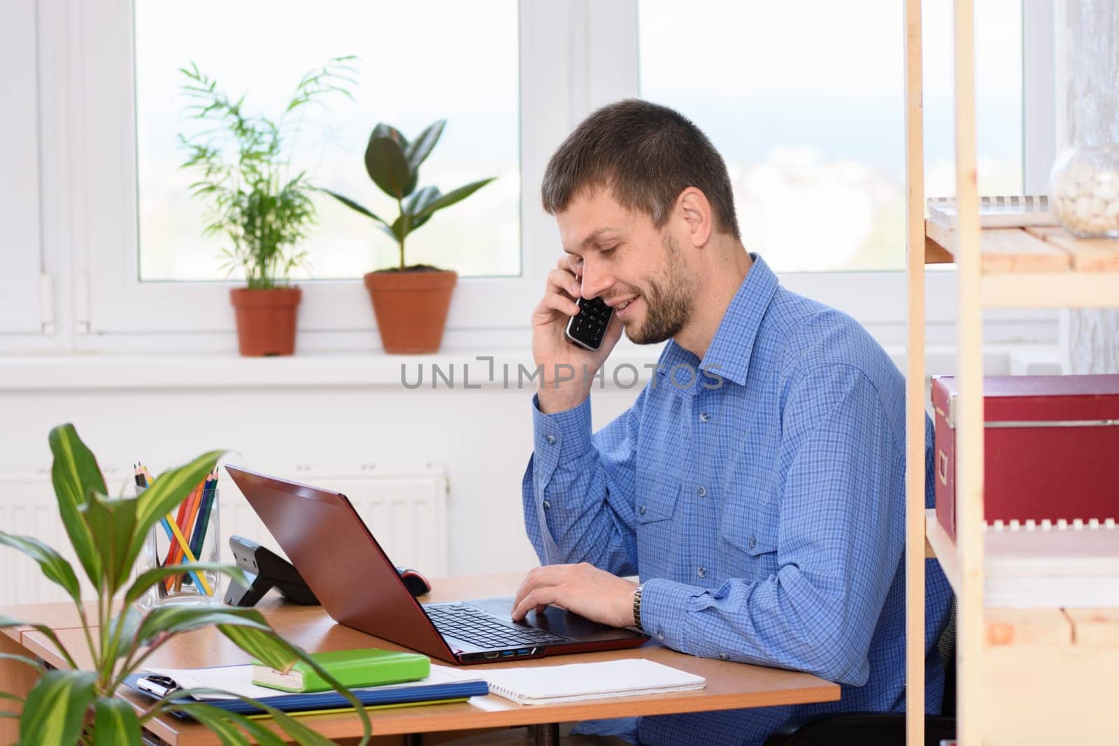 Young businessman talking on the phone in the office and working in a laptop