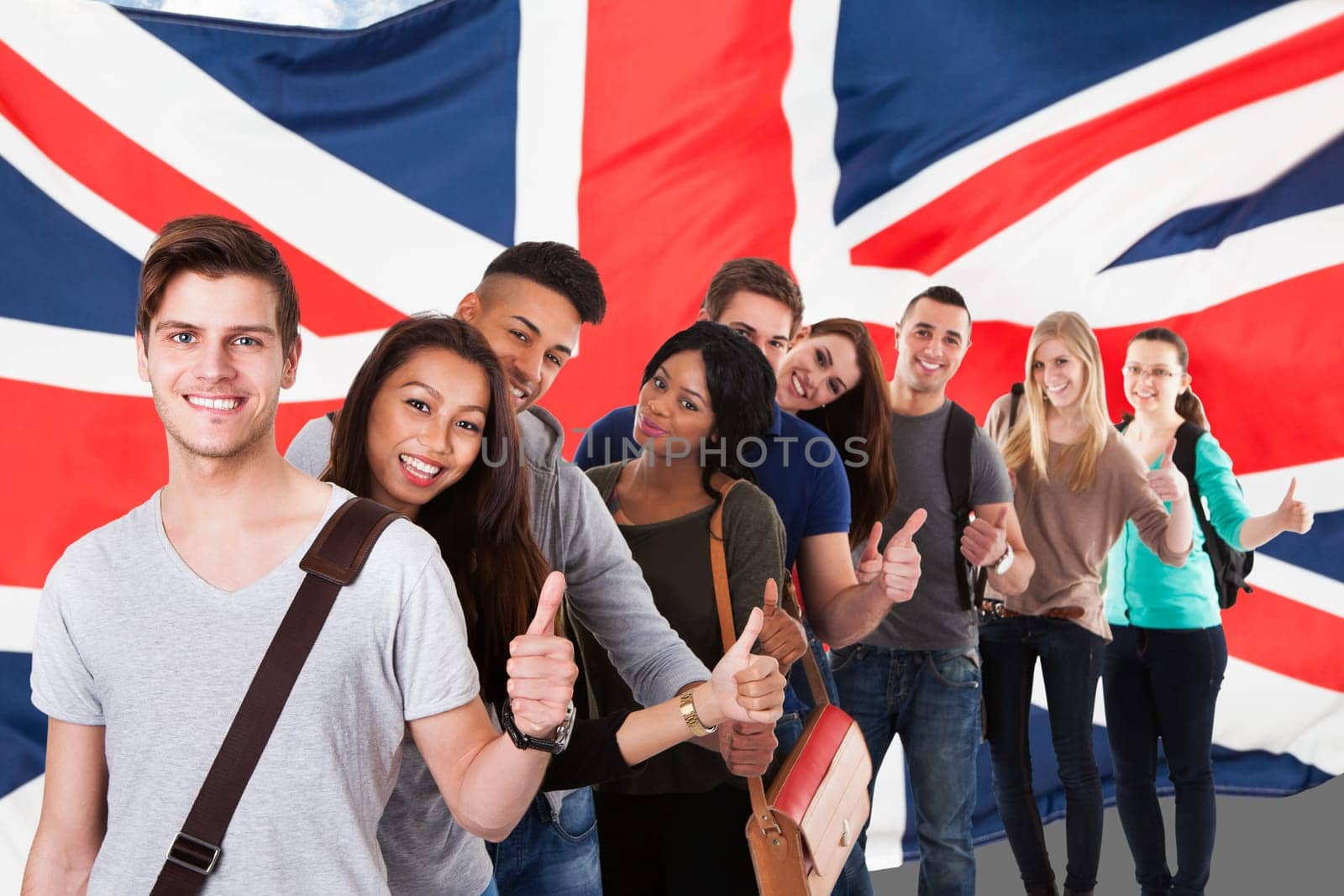 Portrait of college students gesturing thumbs up while standing in a line over white background