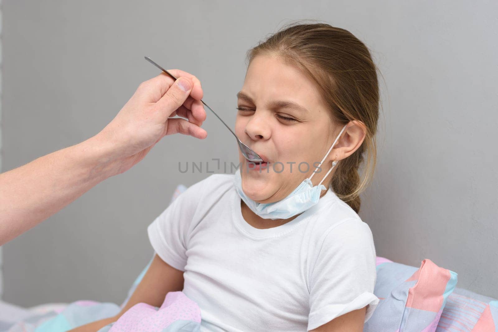 Girl drinking a very nasty medicine from a spoon