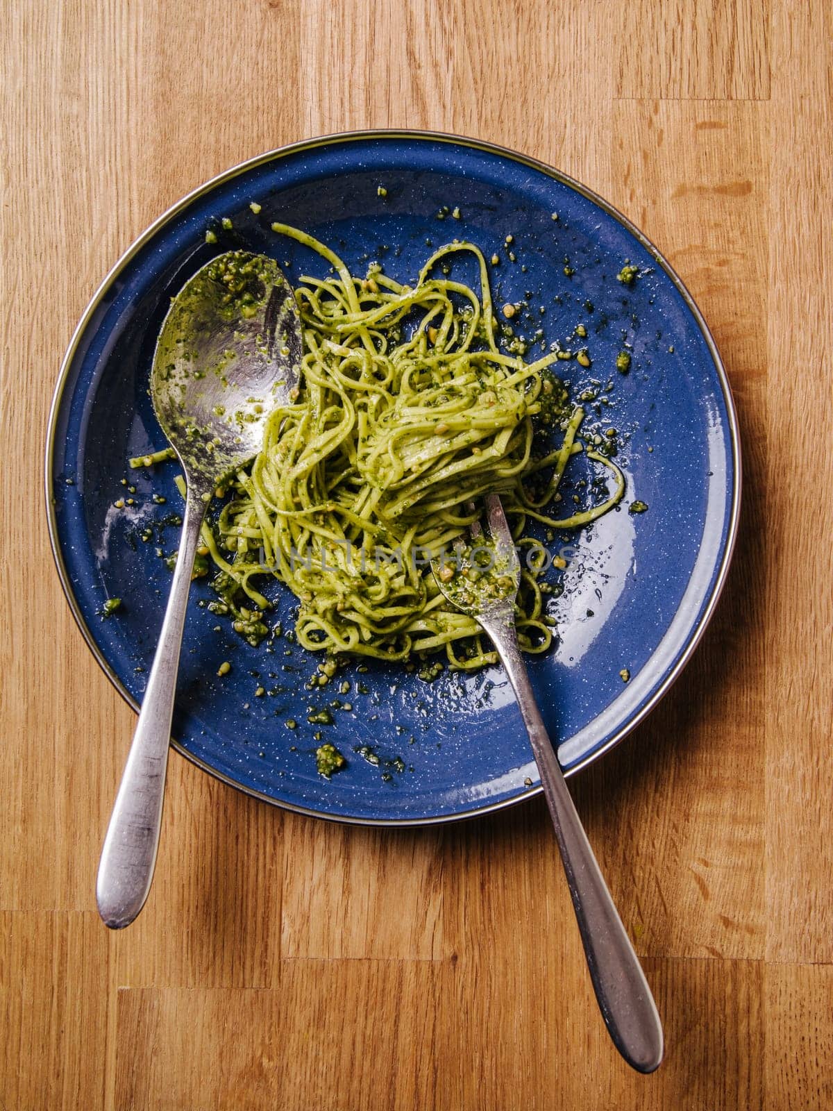 Bowl of basil pesto and pasta on an old wood table.