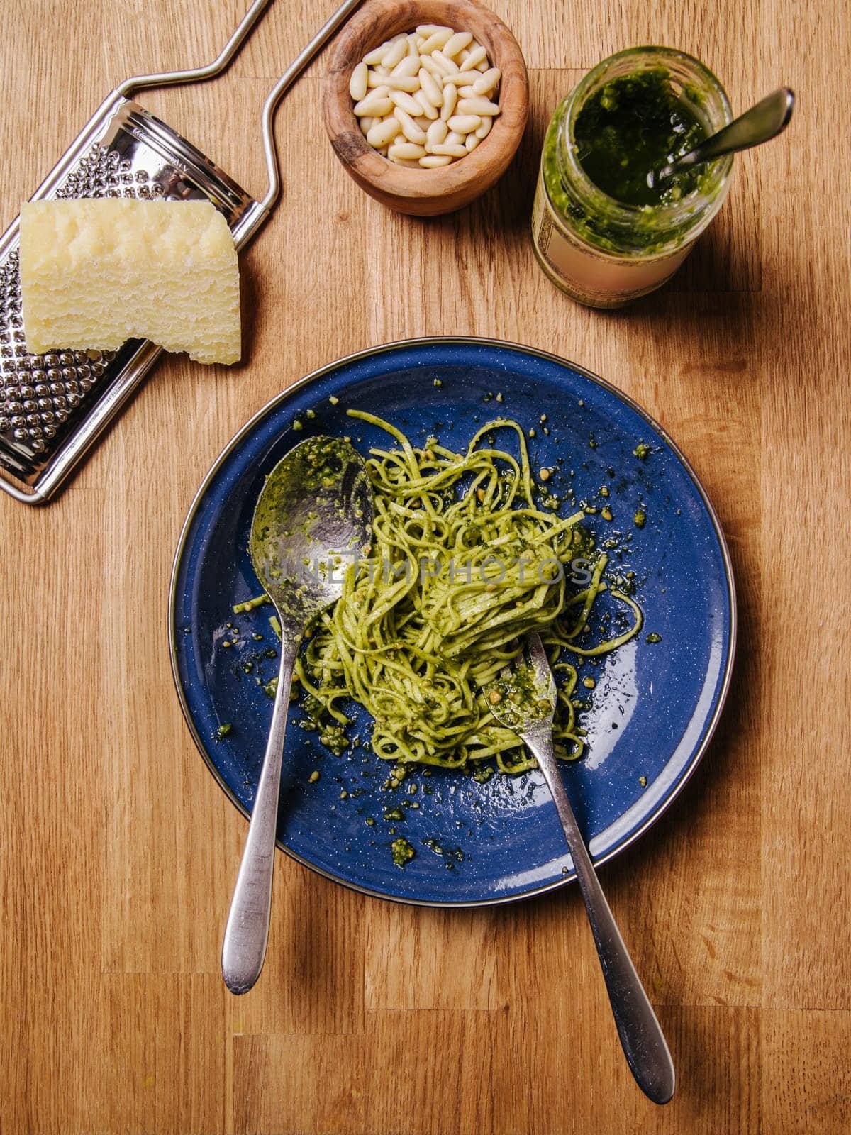 Bowl of basil pesto and pasta on an old wood table.