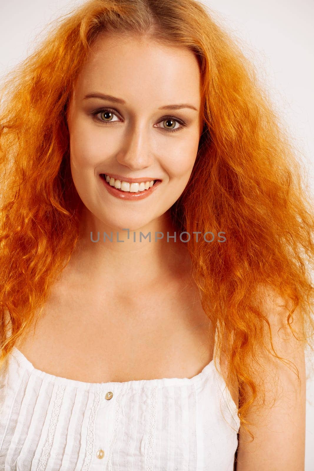 Portrait of a beautiful woman with curly red hair and green eyes.