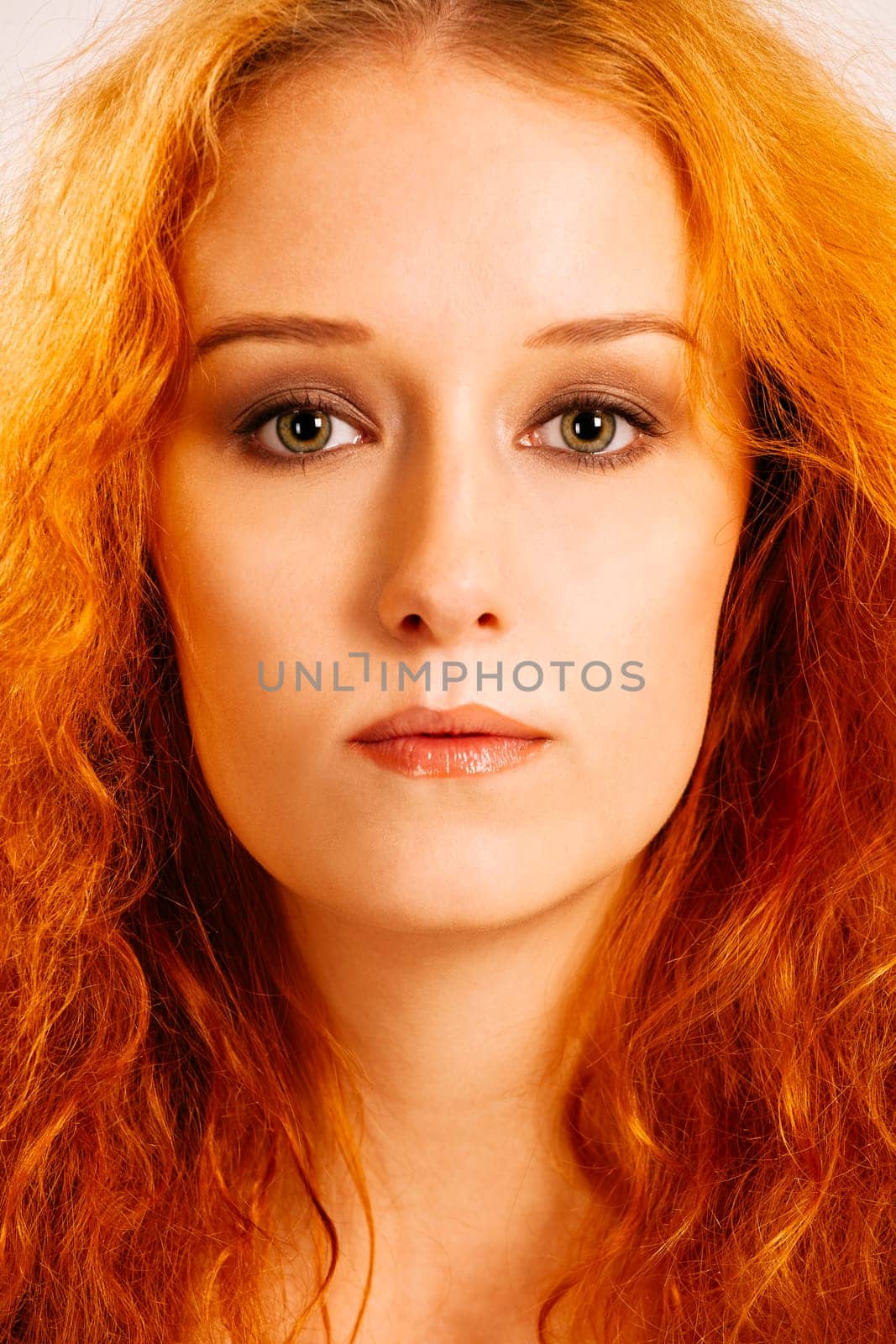 Portrait of a beautiful woman with curly red hair and green eyes.