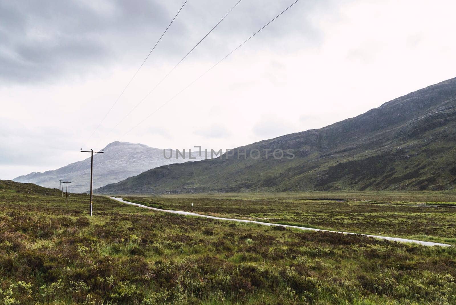 Landscape of mountains, a road and telephone posts in Scotland