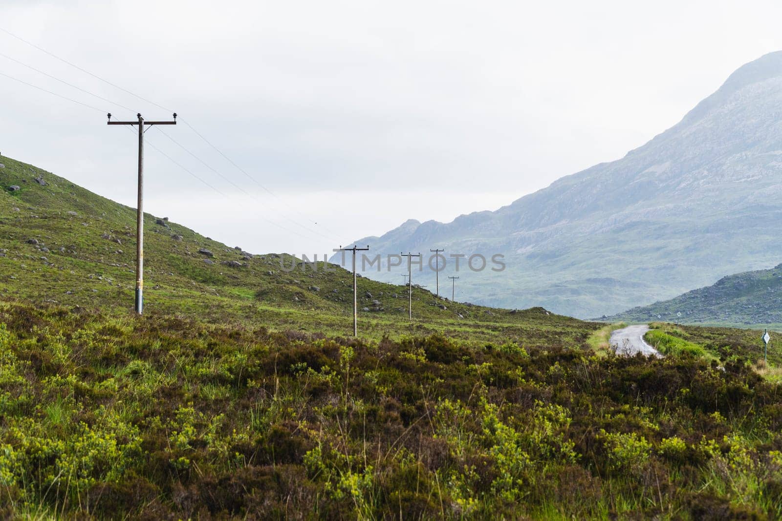 Landscape of mountains, a road and telephone posts in Scotland