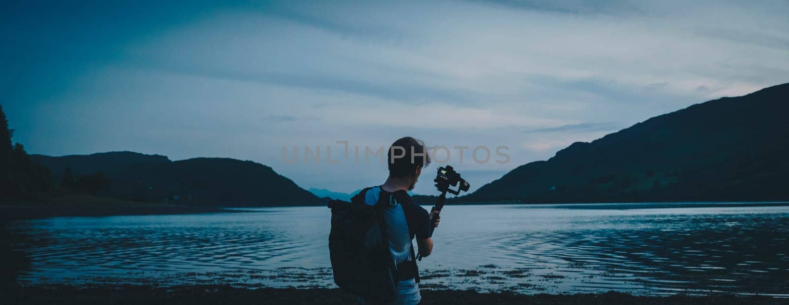 Person using a camera to film and shoot a lake in Scotland during sunset