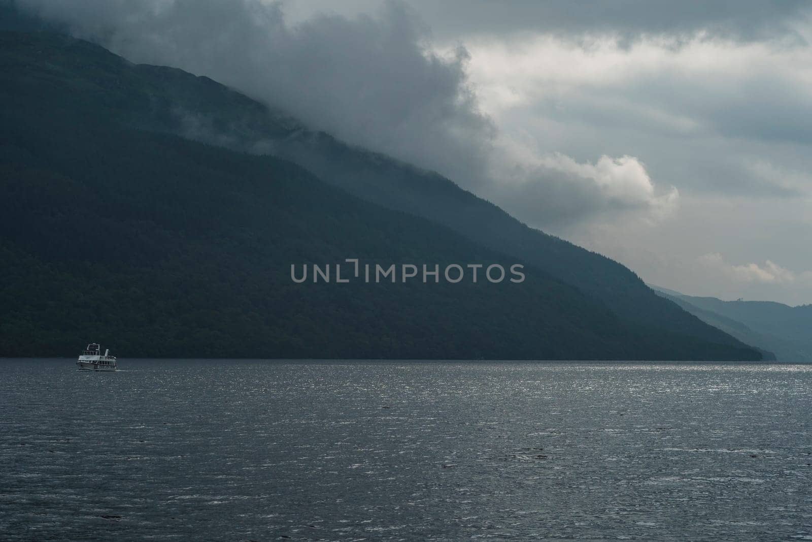 Lake with a boat in Scotland Highlands with calm sea and mountains ashore