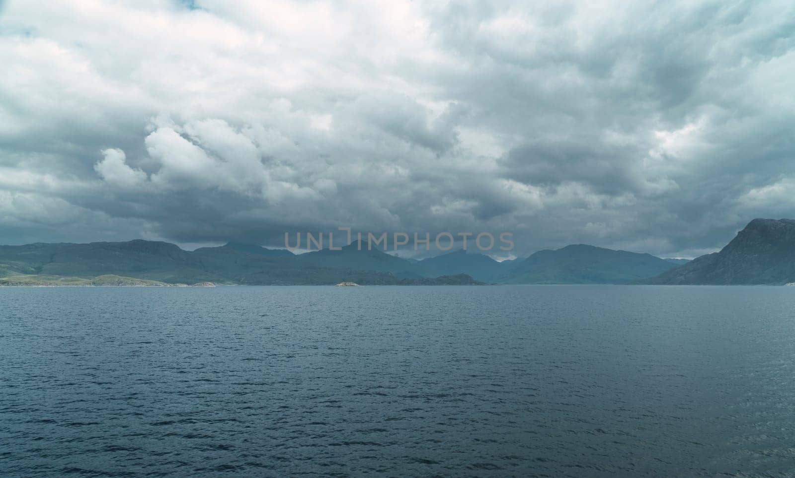 Lake with a boat in Scotland Highlands with calm sea and mountains ashore