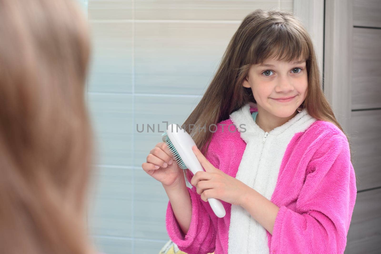 Girl combing long hair at home with a comb