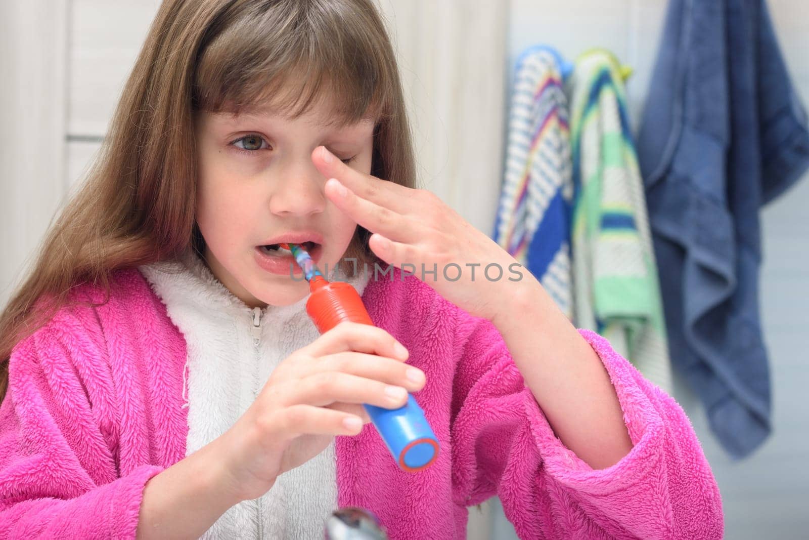Sleepy girl brushes her teeth in the early morning