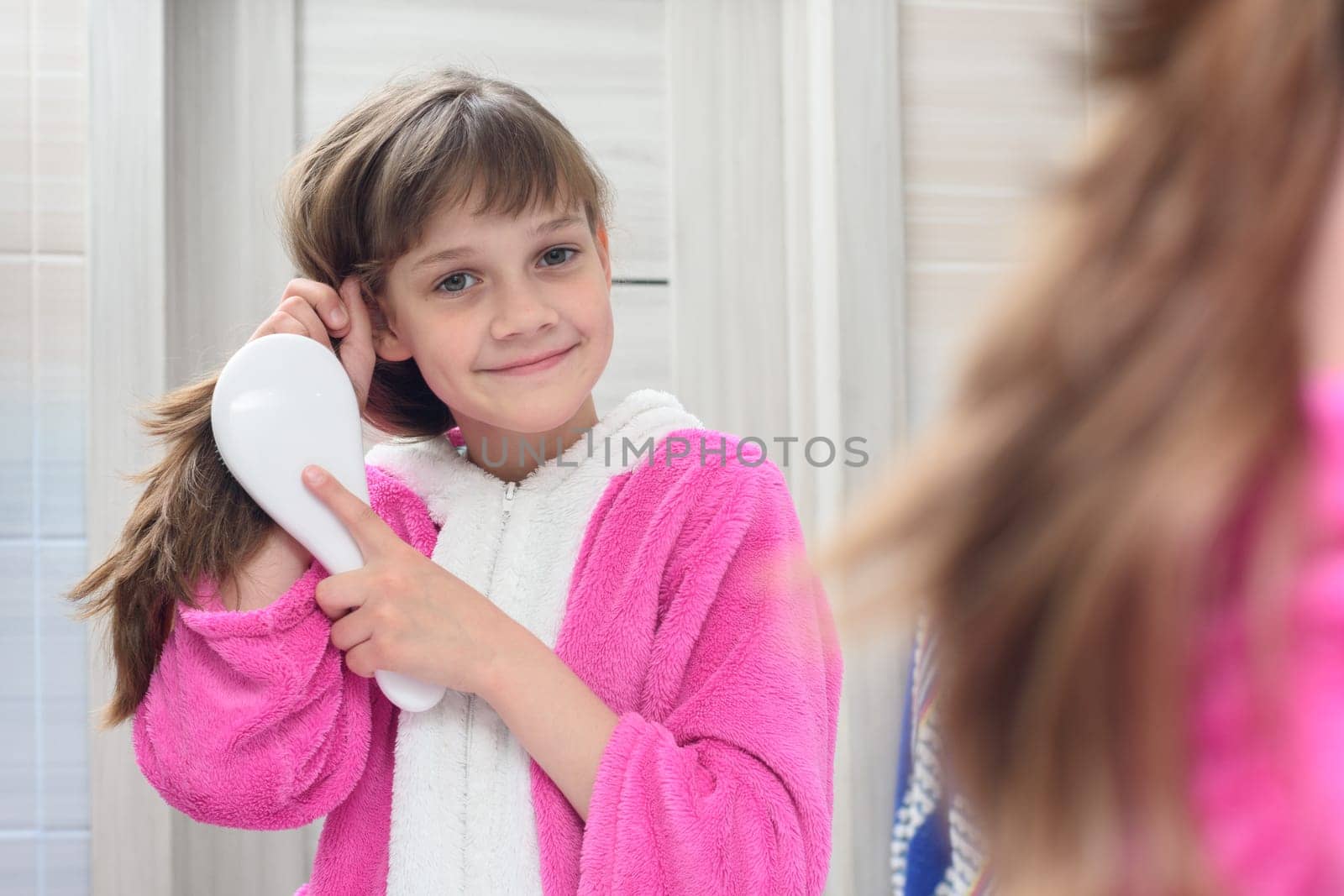 Happy girl combing hair in the bathroom