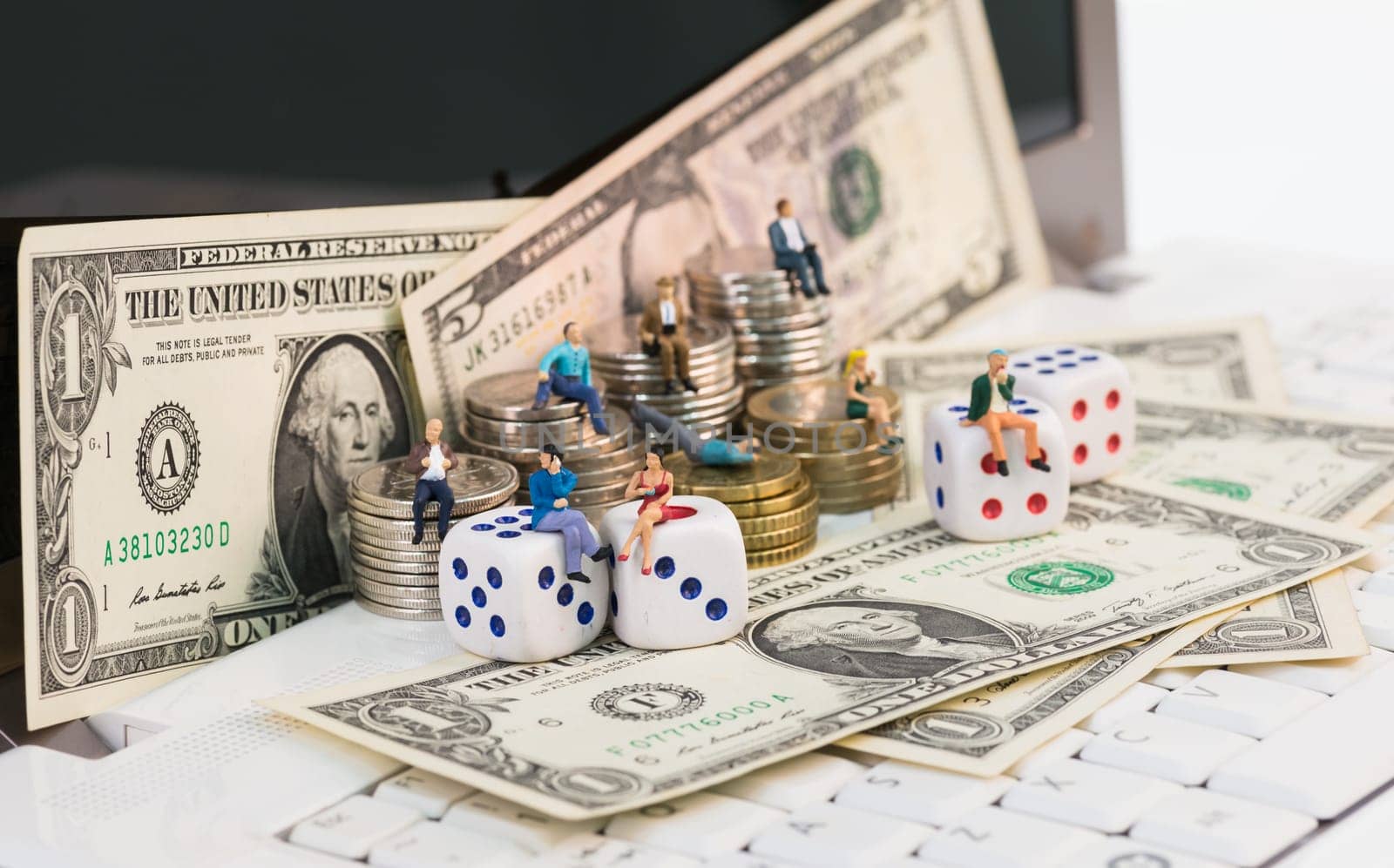 Online gambling concept with miniature people and coins on top of a notebook
