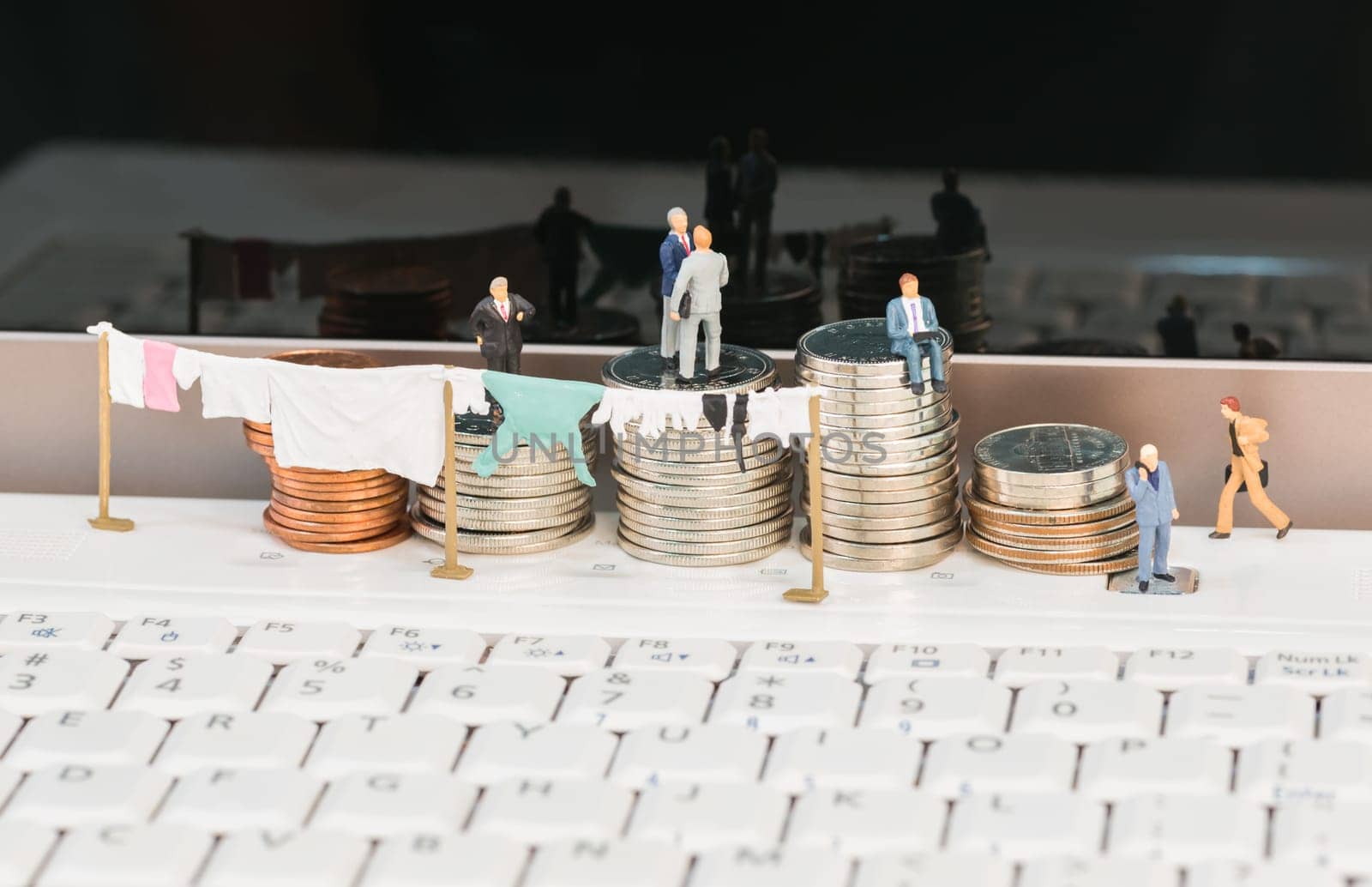 Money laundering concept with miniature people, clothesline and coins on top of a notebook