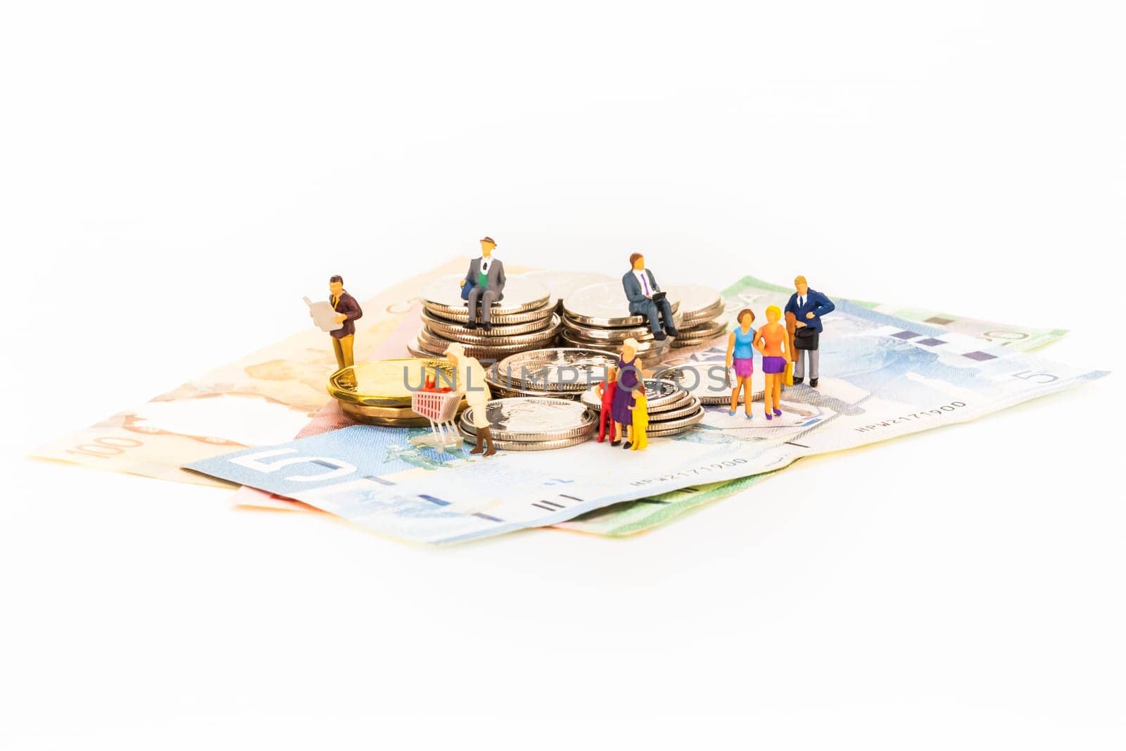 Miniature people and coins on top of banknotes