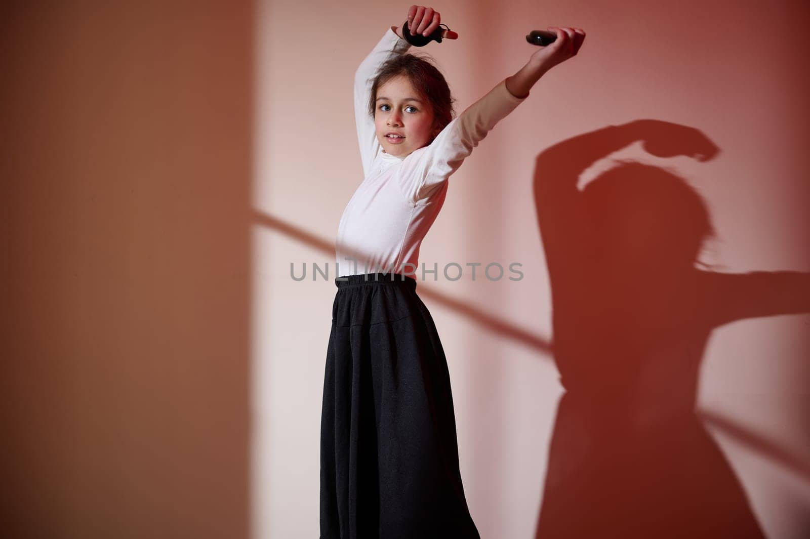 A young girl dances gracefully in an artfully lit environment, showcasing expressive movements and dynamic poses, celebrating creativity and beauty.