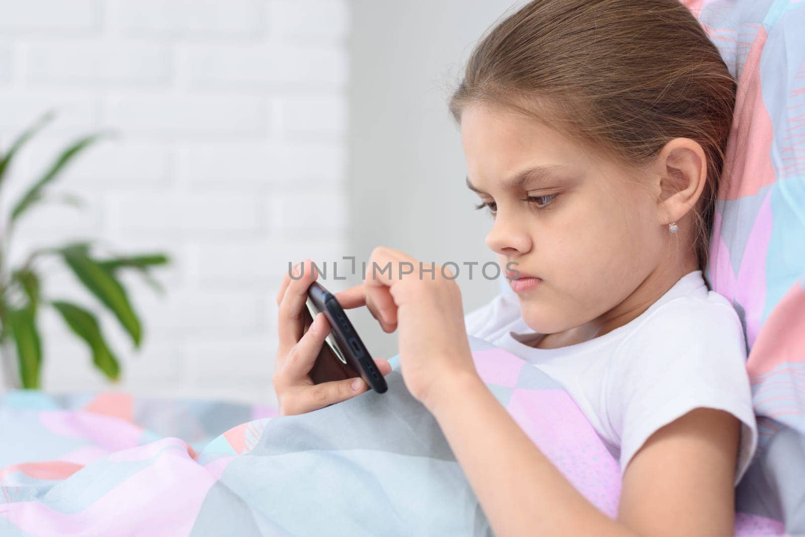 Girl playing on a cell phone while lying in bed