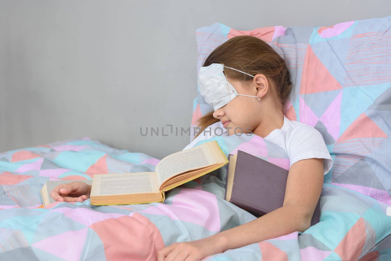 The sick girl fell asleep lying in bed and pulled the mask over her face