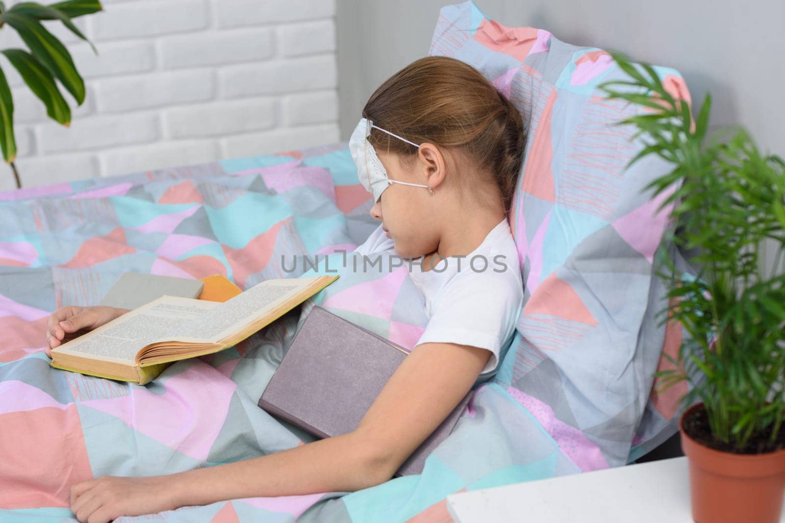 the girl fell asleep lying in bed and reading books, a medical mask is put on her eyes