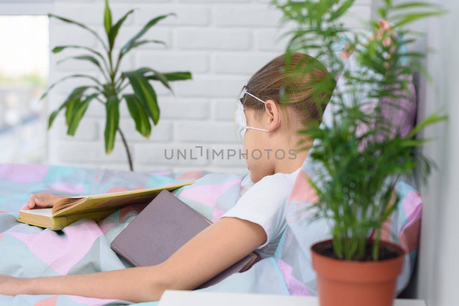 The sick girl lies in bed and fell asleep reading a book