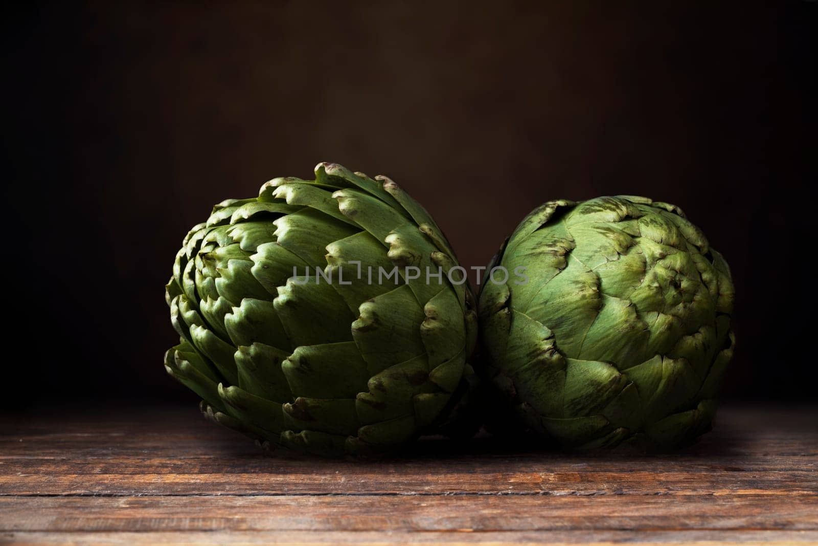 Two artichokes on dark wooden surface