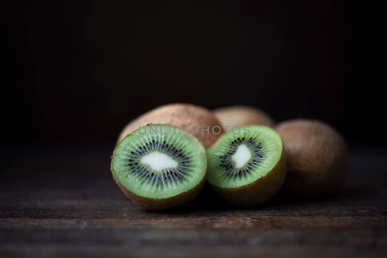 Fresh kiwi on dark wooden table with dark background and copy space.