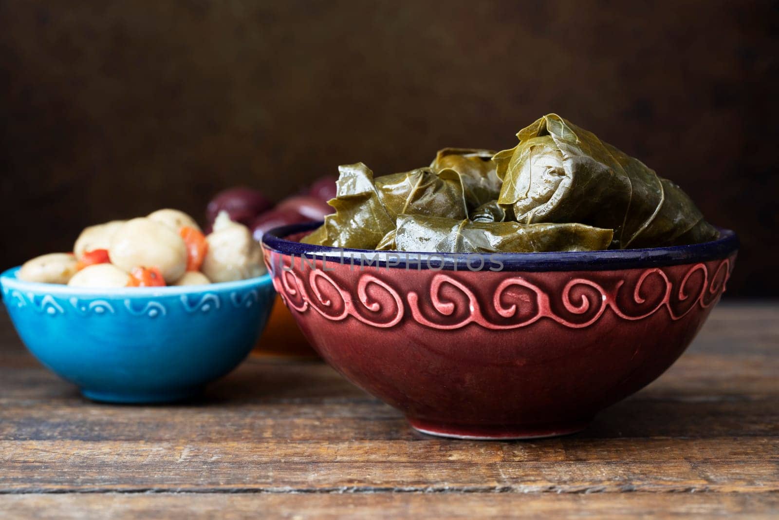 Fresh dolmatas with marinated mushrooms and olives tapas on wooden table.
