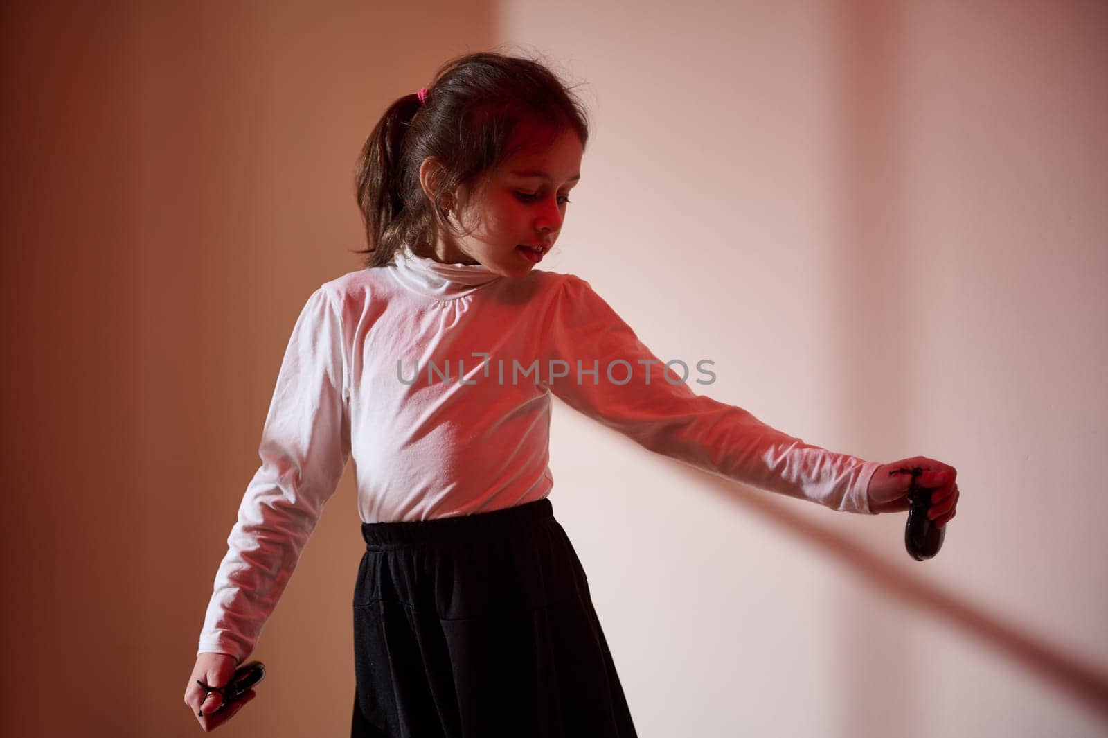 A young girl in a white blouse performs a flamenco dance, illuminated by dramatic red and white lighting. Artistic composition highlighting emotion and cultural expression.