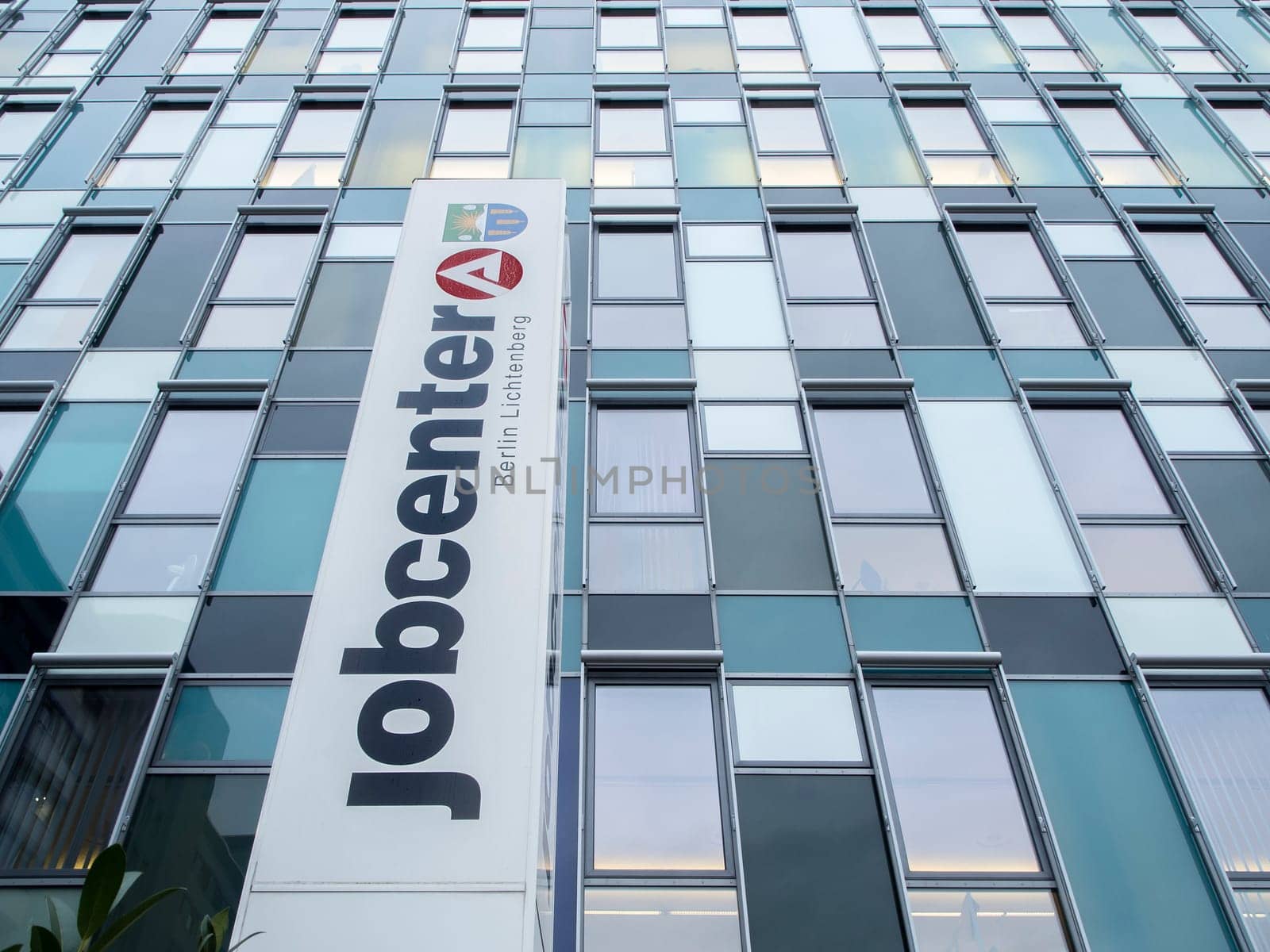 Berlin, Germany - January 27, 2020: Low angle view of the window front with large vertically mounted inscription of the job center in Berlin-Lichtenberg.