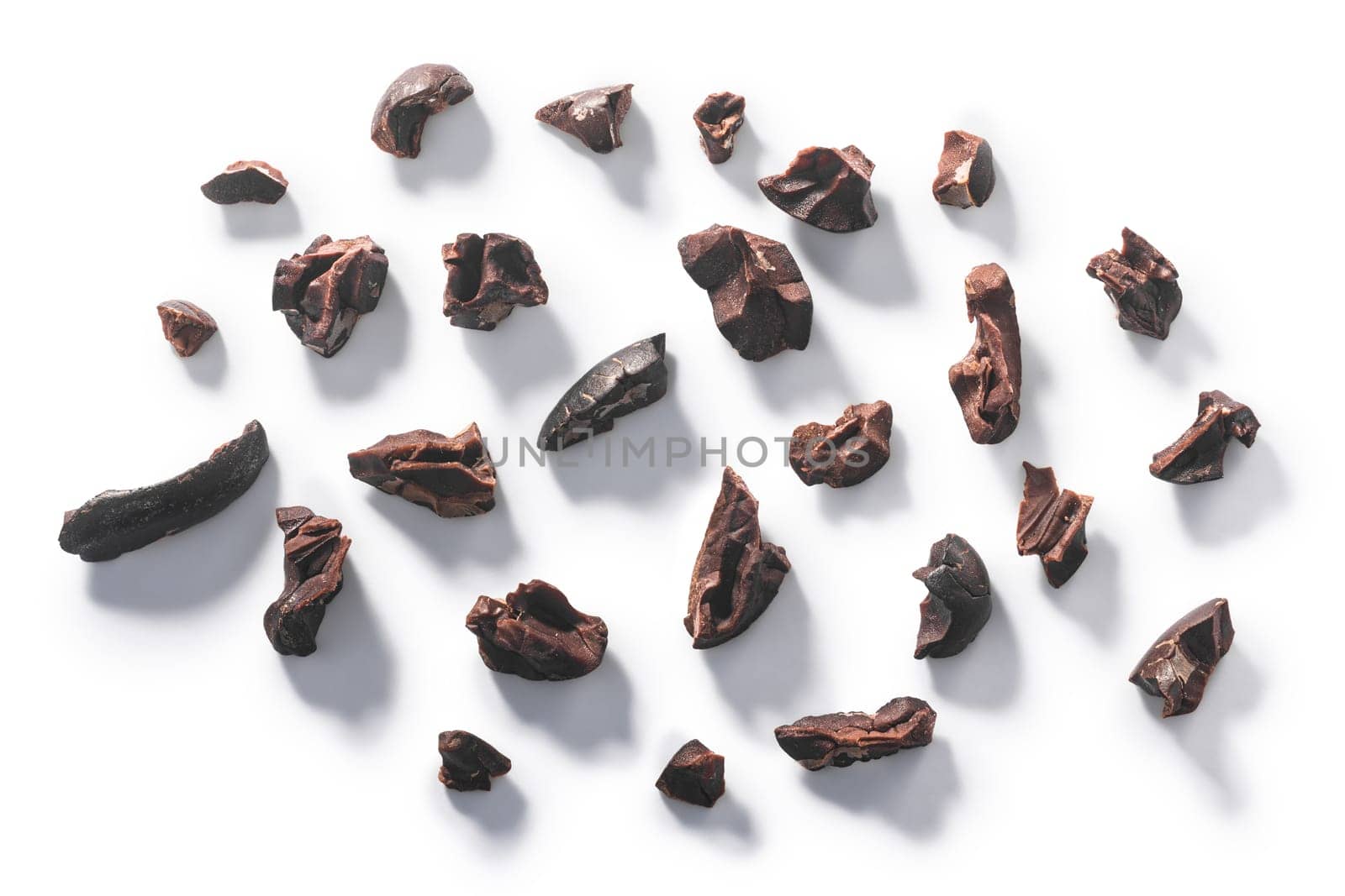 Cacao nibs, a pieces of broken cocoa beans isolated, top view