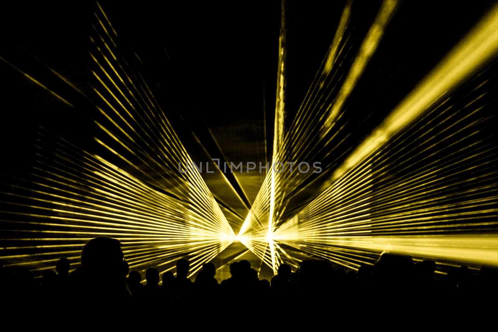 Luxury entertainment with audience silhouettes in nightclub event, festival or New Year's Eve. Beams and rays shining colorful lights.
