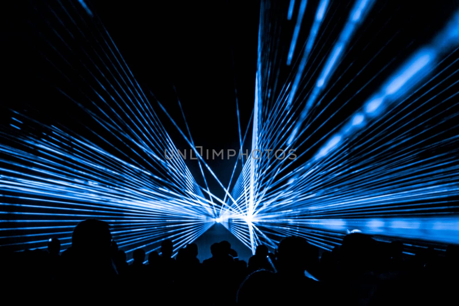 Luxury entertainment with audience silhouettes in nightclub event, festival or New Year's Eve. Beams and rays shining colorful lights.