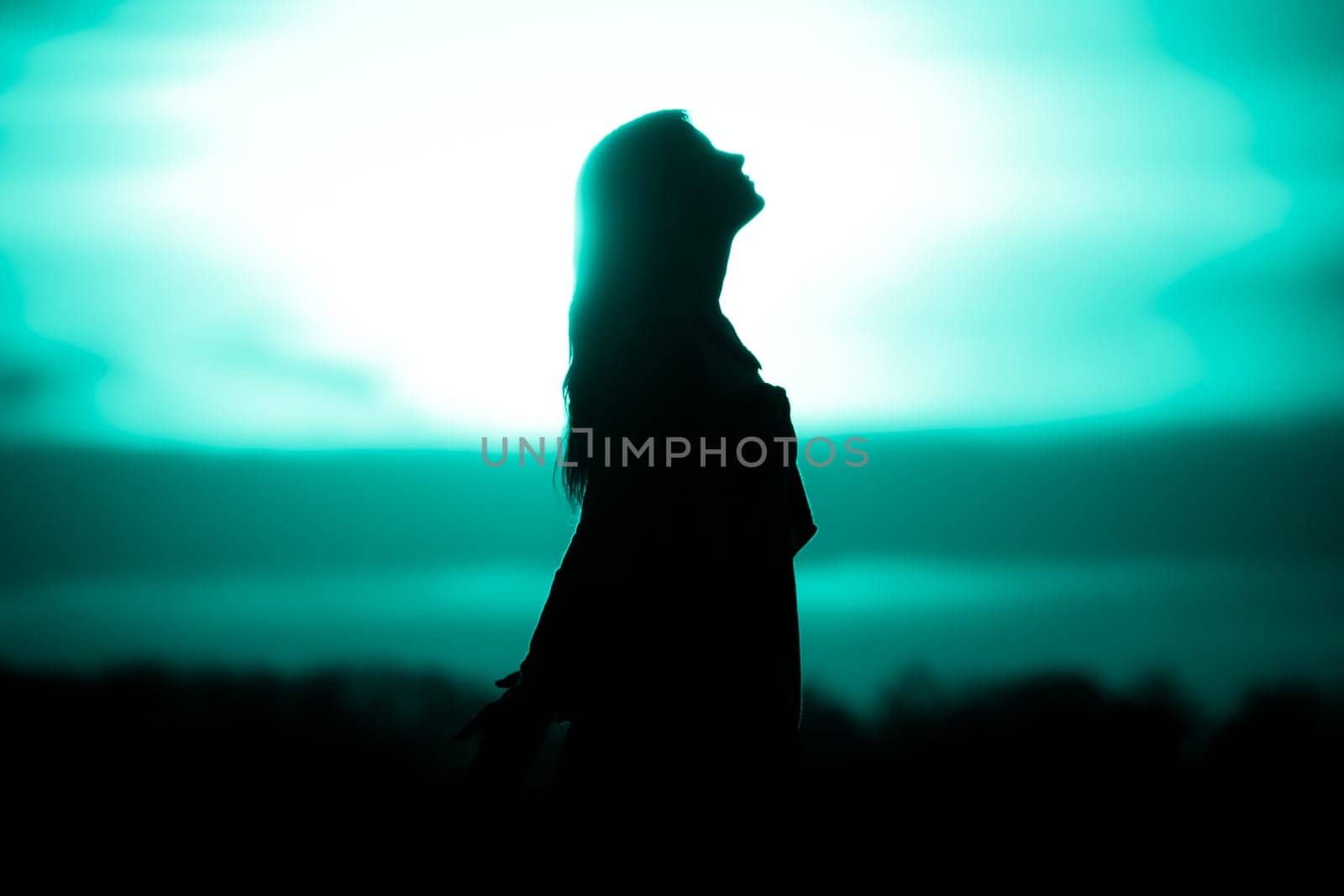 Silhouette in front of sunset or sunrise in summer nature. Symbol for healing burnout therapy, wellness relaxation or resurrection.
