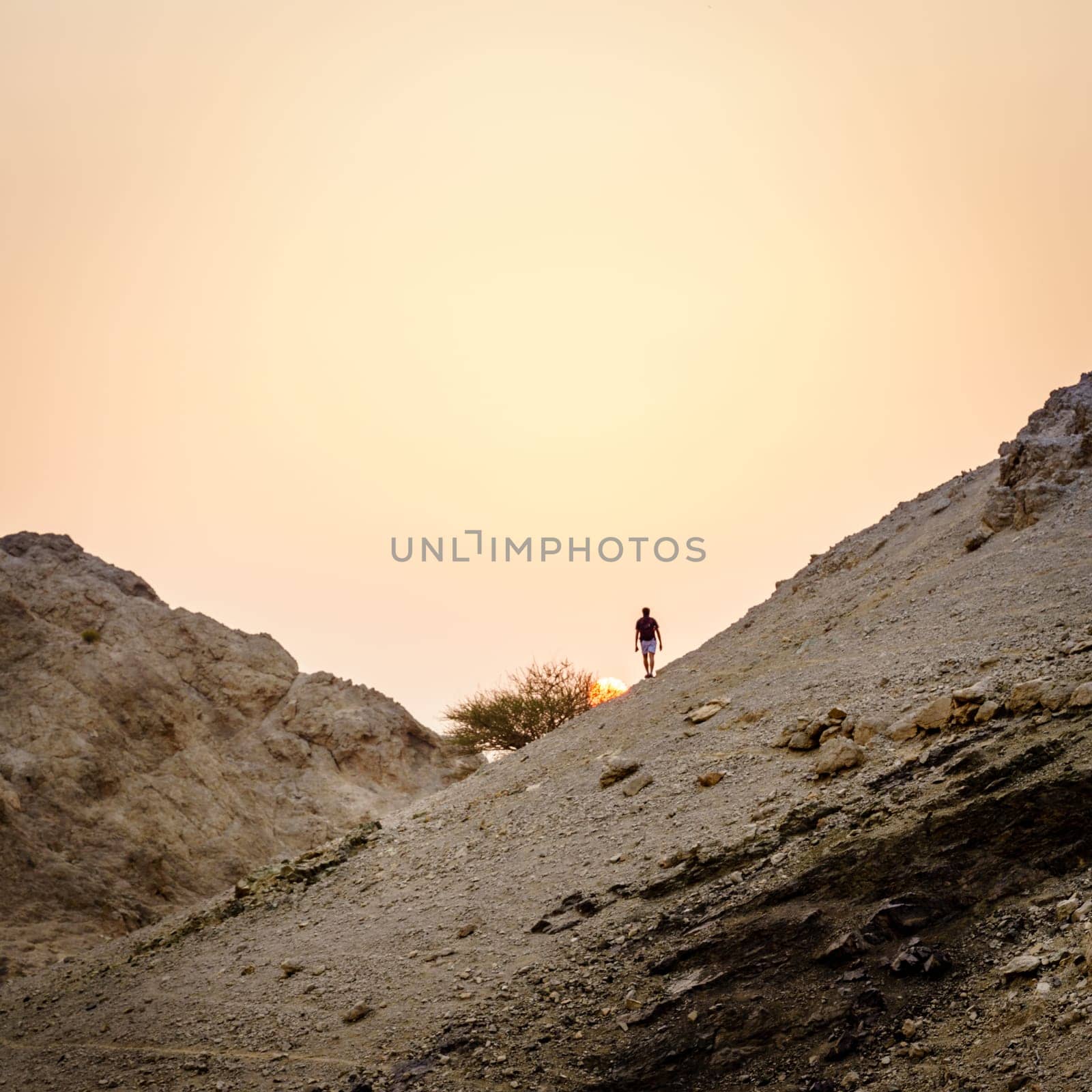 Hiker is watching sunset in Hajar Mountains of Ras Al Khaimah in UAE