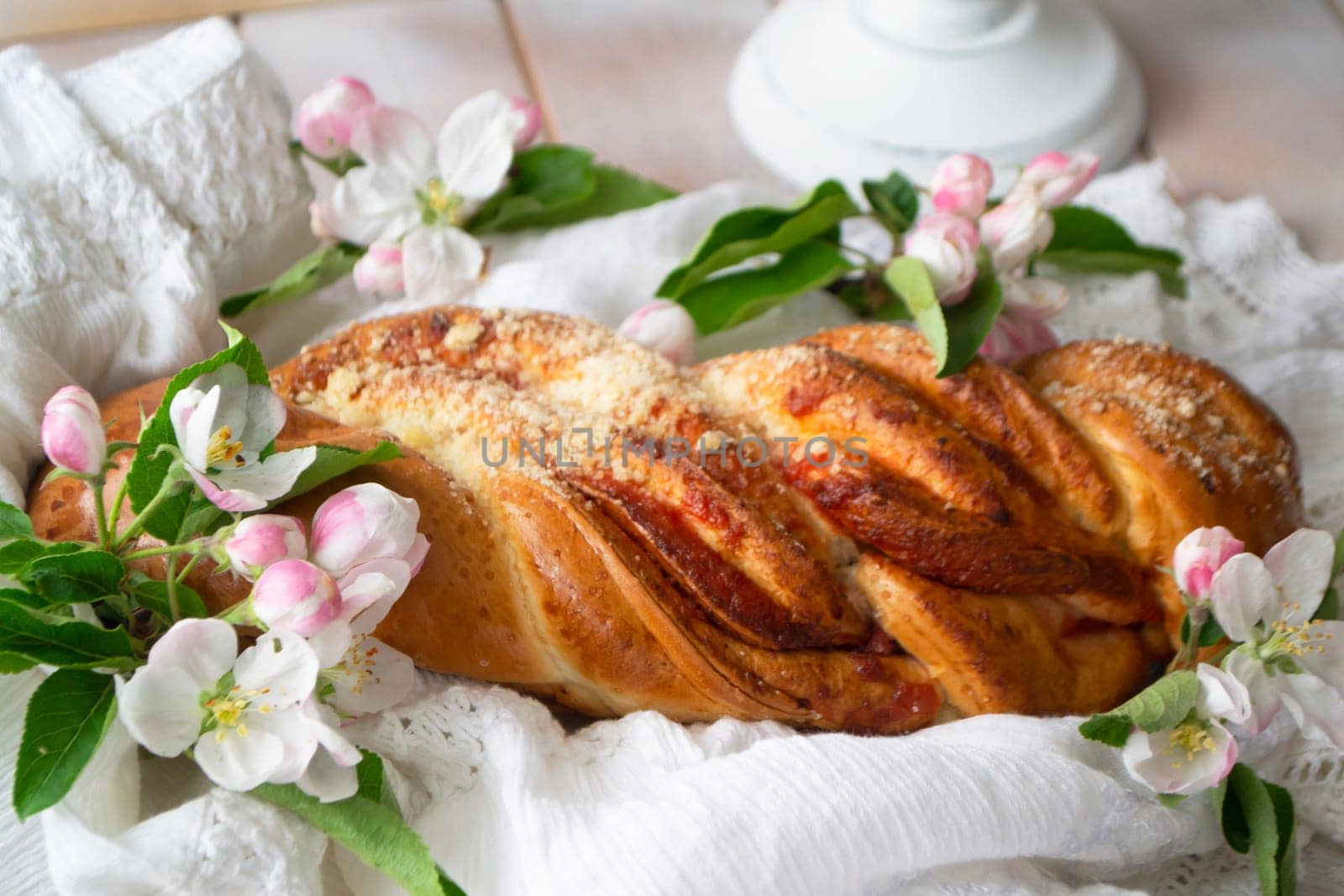 wicker sweet bread with strawberries. Sweet wheat bun on a wooden background and spring flowers. Rustic style.