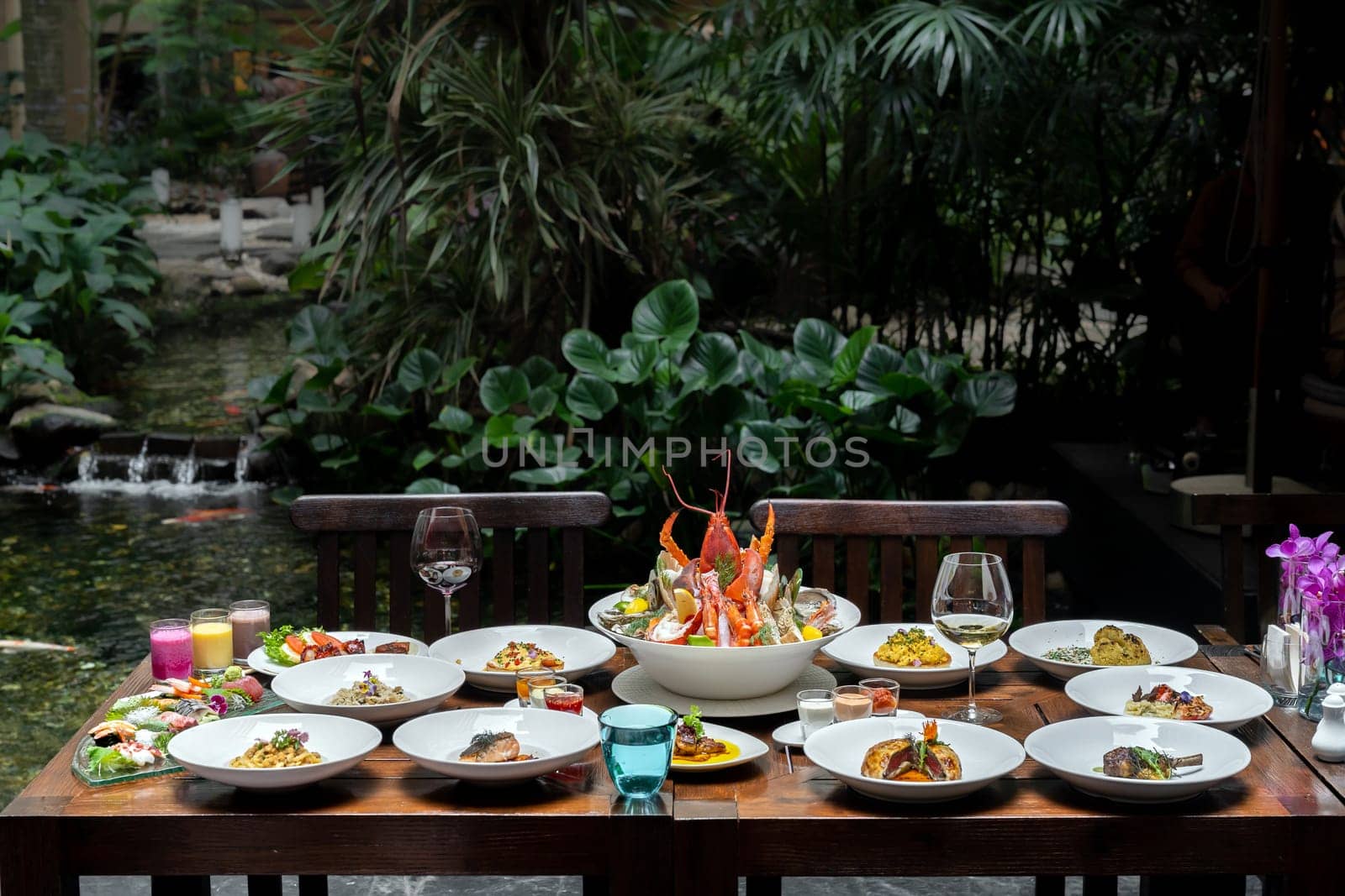 Side view premium variety of international food in garden of restaurant of lobster shrimp steak beef lamb pasta spaghetti risotto rice sushi sashimi and wine using for buffet food drink background.
