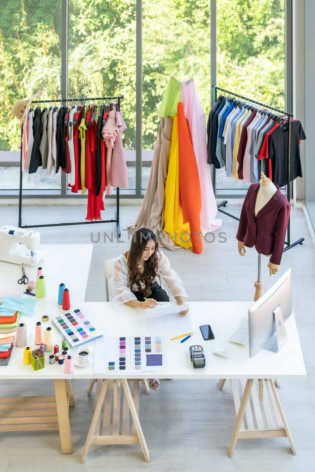 Top view of young adult asian fashion designer drawing and sketching her work at home as atelier studio with colour palette. Using for entrepreneur small business startup concept.