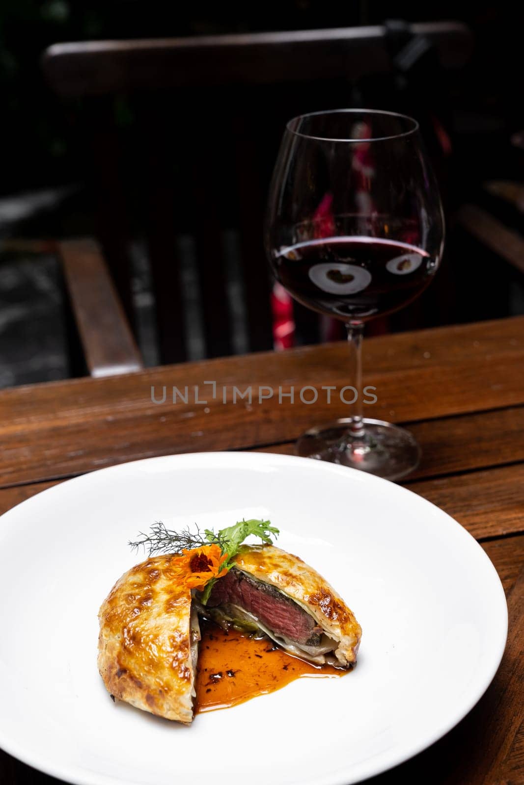 Roasted Beef Wellington with gravy brown savory sauce, international gourmet cuisine of stuff beef meat in baked bread puff with glass of red wine. Unising for recipe menu pf food and drink industry.