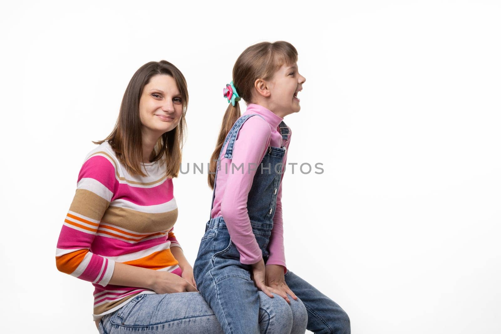 On the mothers lap, a daughter sits and laughs joyfully turning to the side