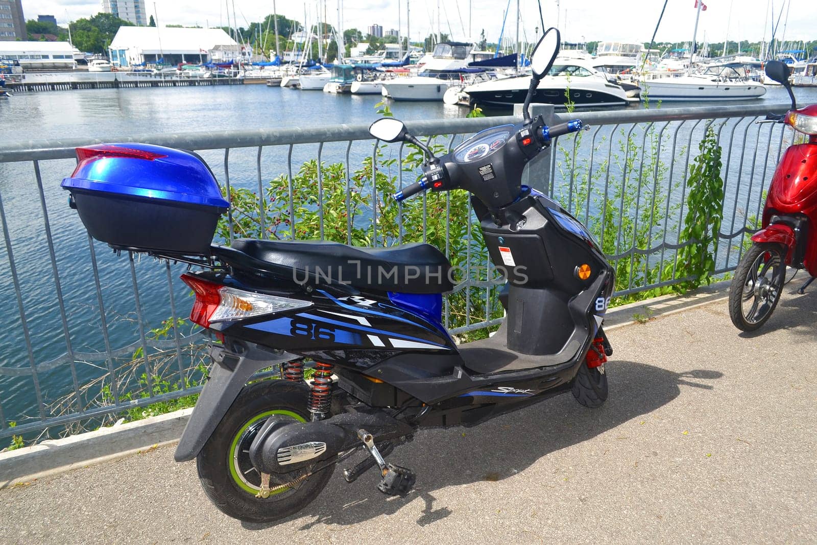 Two motorbikes sitting on the promenade on the harbor of Hamilton.with many sailboats in the background.