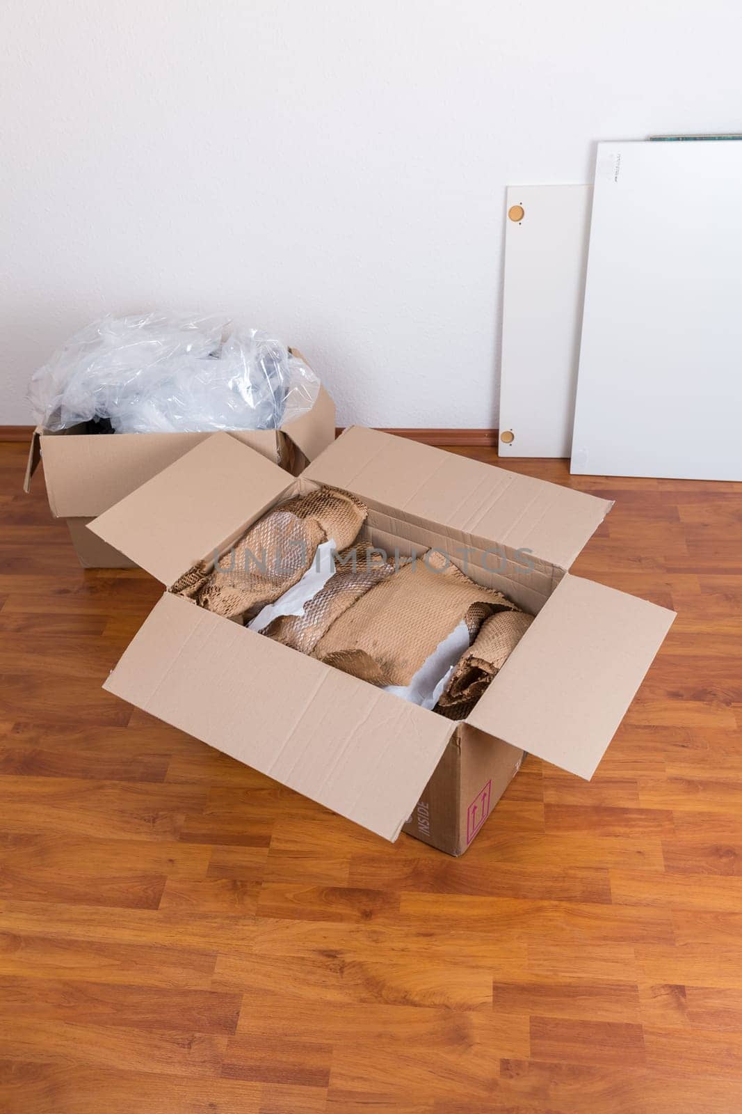 Moving boxes with packing material for fragile items on the floor. Concept of moving in or out.