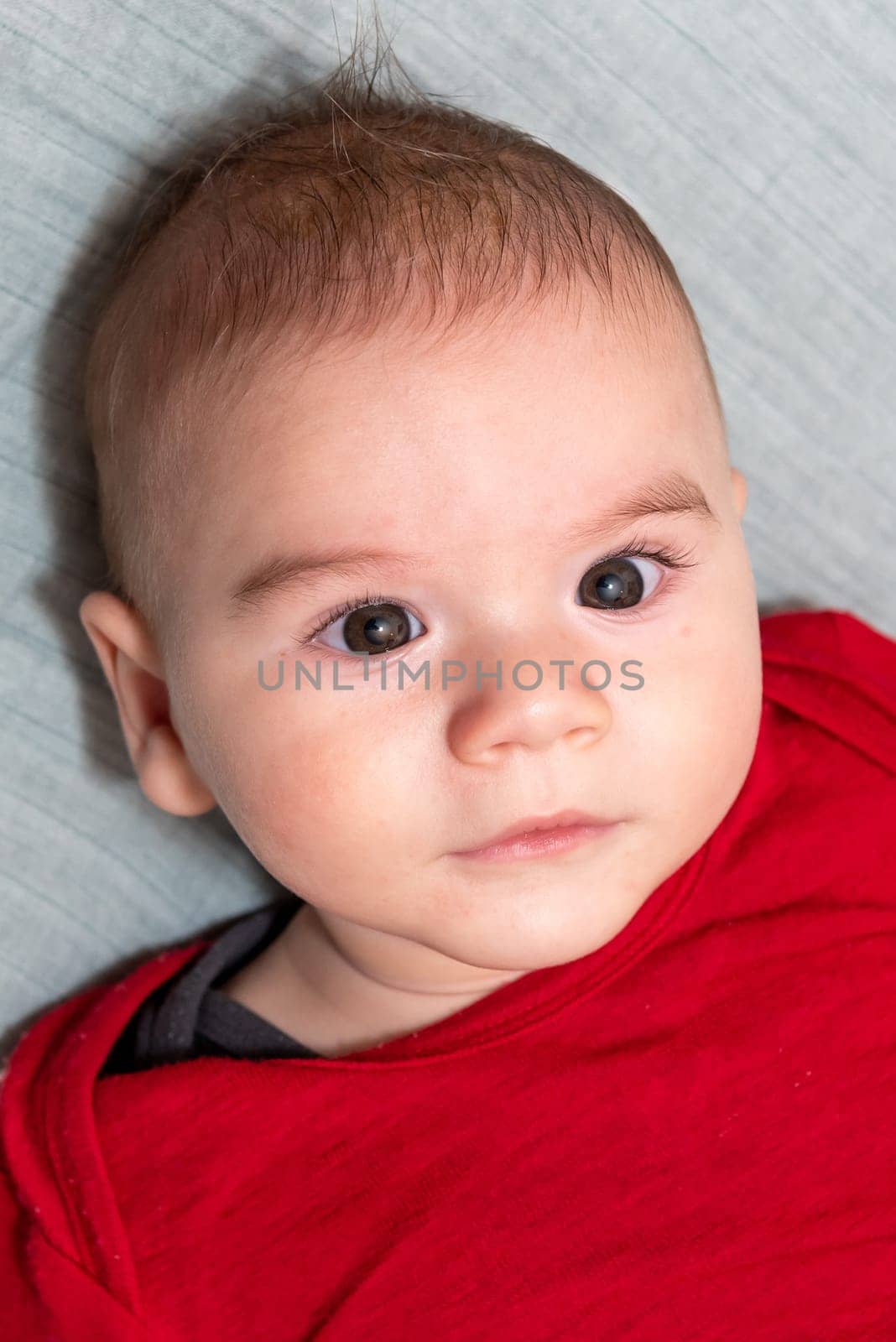 Adorable 6 months old little baby boy on his back looking up
