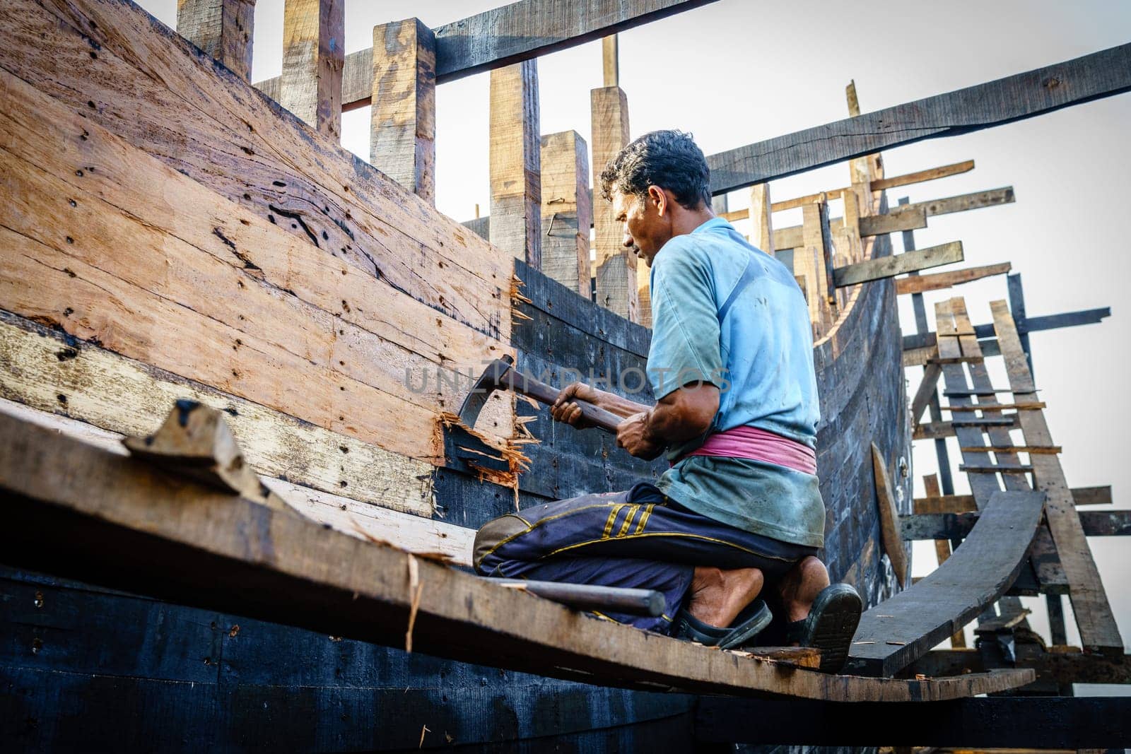 Chittagong, Bangladesh, December 22, 2017: Man is woring on a traditional fishing boat at a shipyard by the Karnaphuli River near Chittagong, Bangladesh