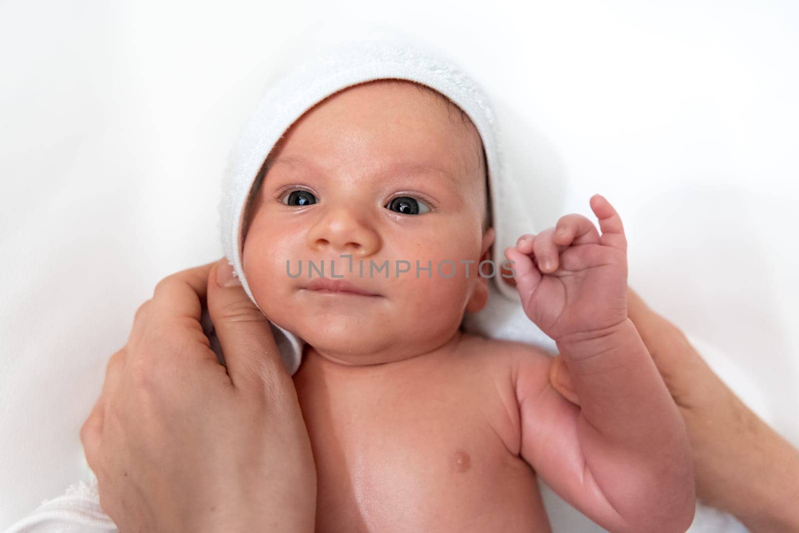 Adorable 2 months old little baby boy on towel after bath in his mother's hands