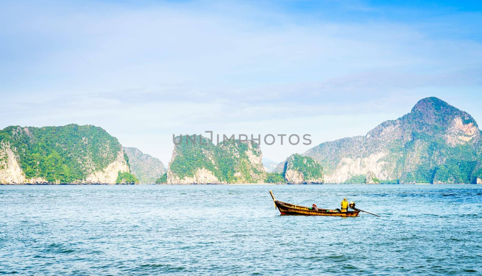 Traditional Thai motor boat in the Andaman Sea with Phuket coastline in the backdrop