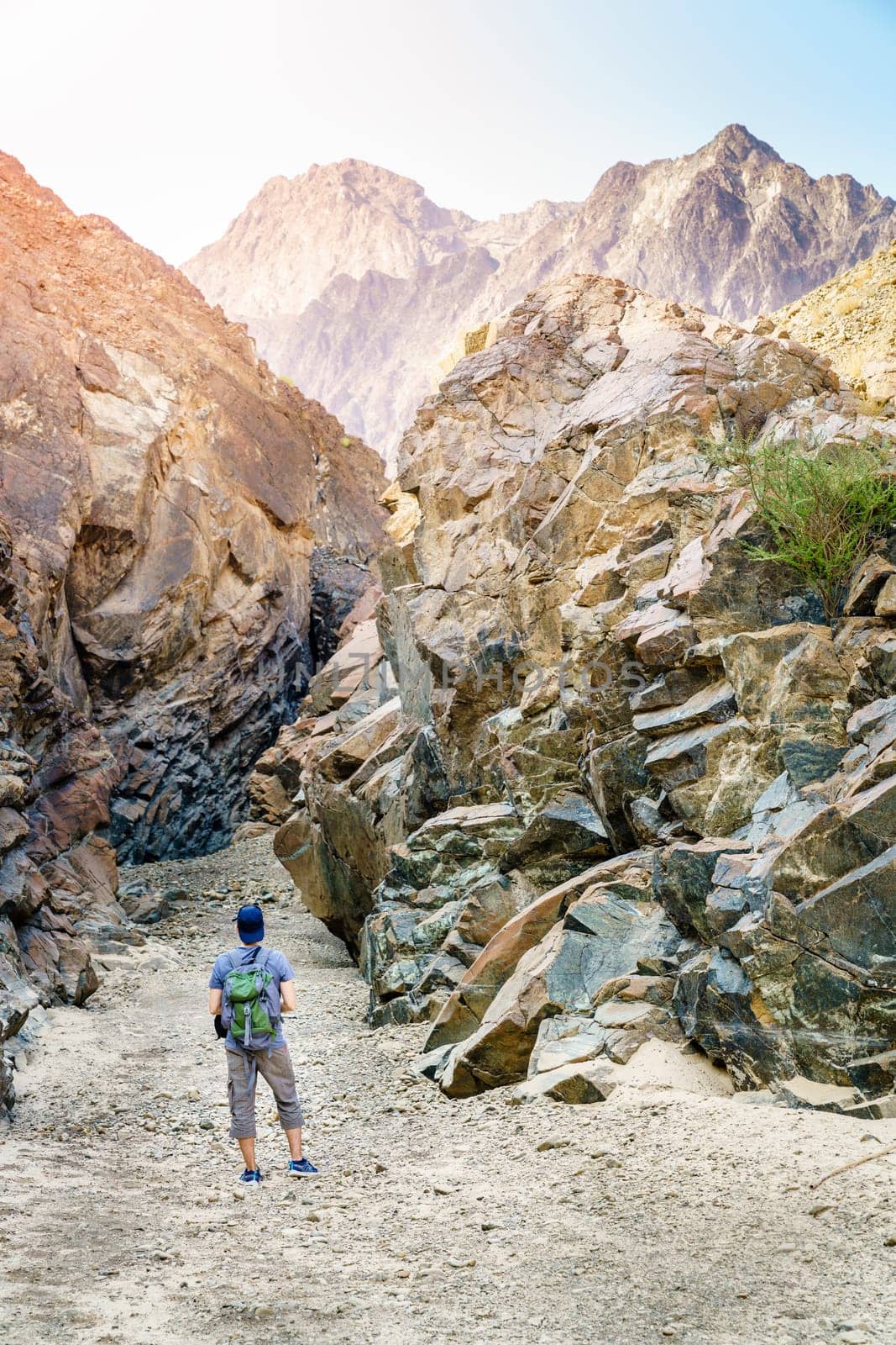 A man is hiking through a wadi in Hajar Mountains near Hatta, UAE